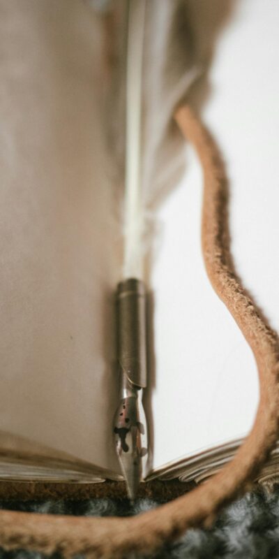 A vintage quill pen resting on an open journal, creating a nostalgic writing scene.