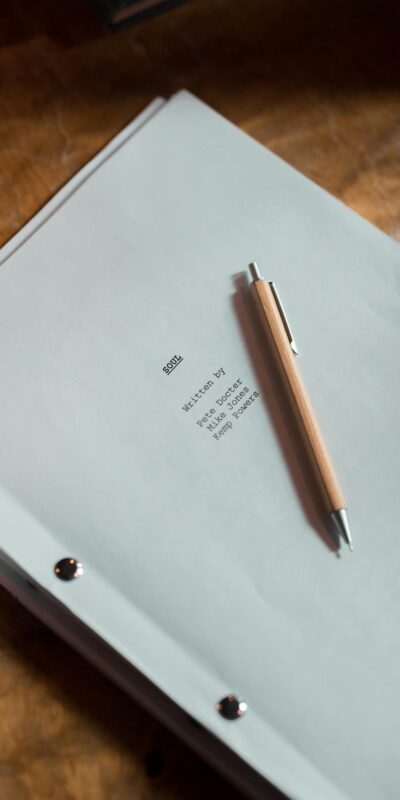 An overhead shot of a script and pen on a wooden desk, perfect for writing and creativity themes.