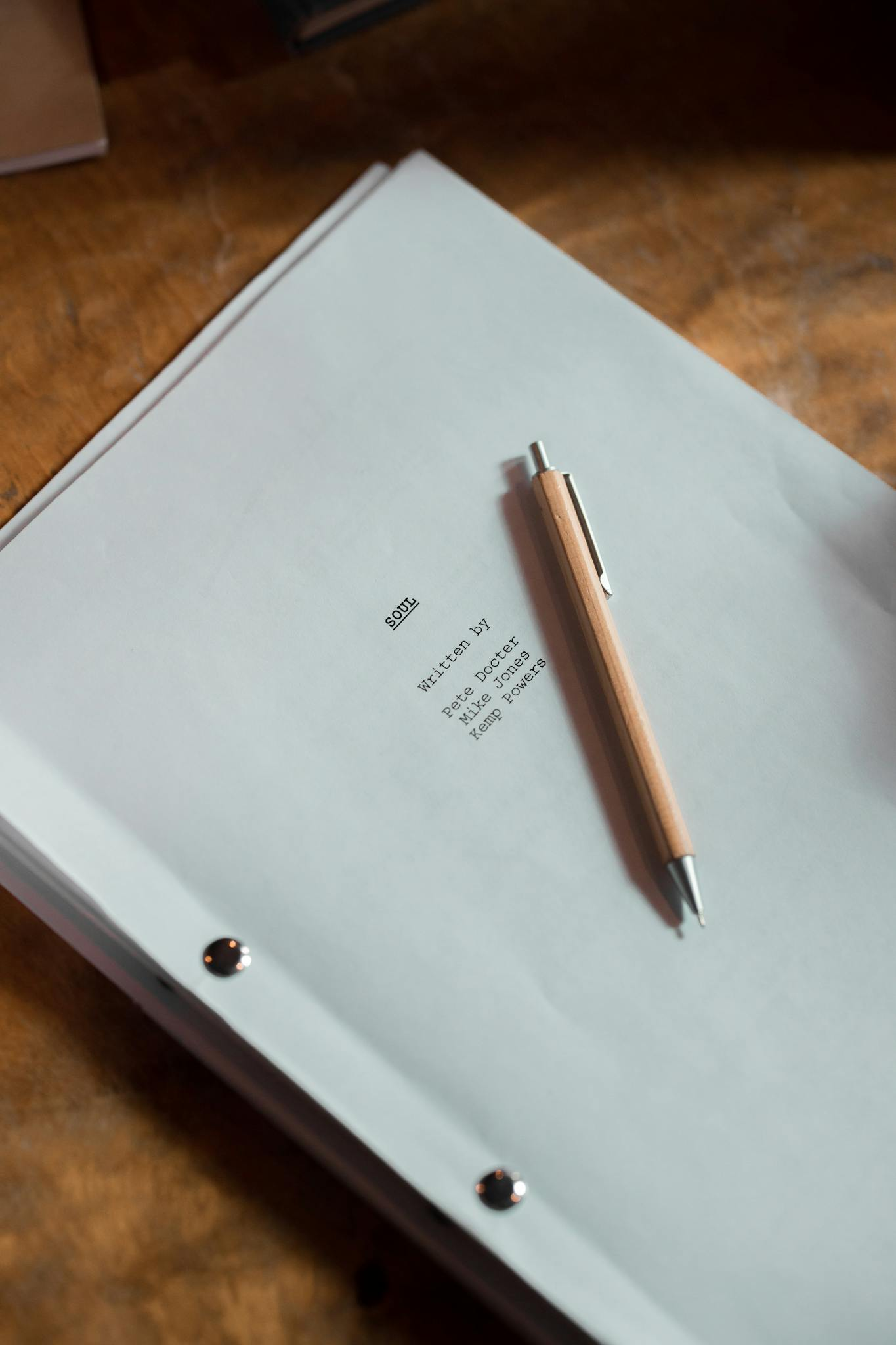 An overhead shot of a script and pen on a wooden desk, perfect for writing and creativity themes.
