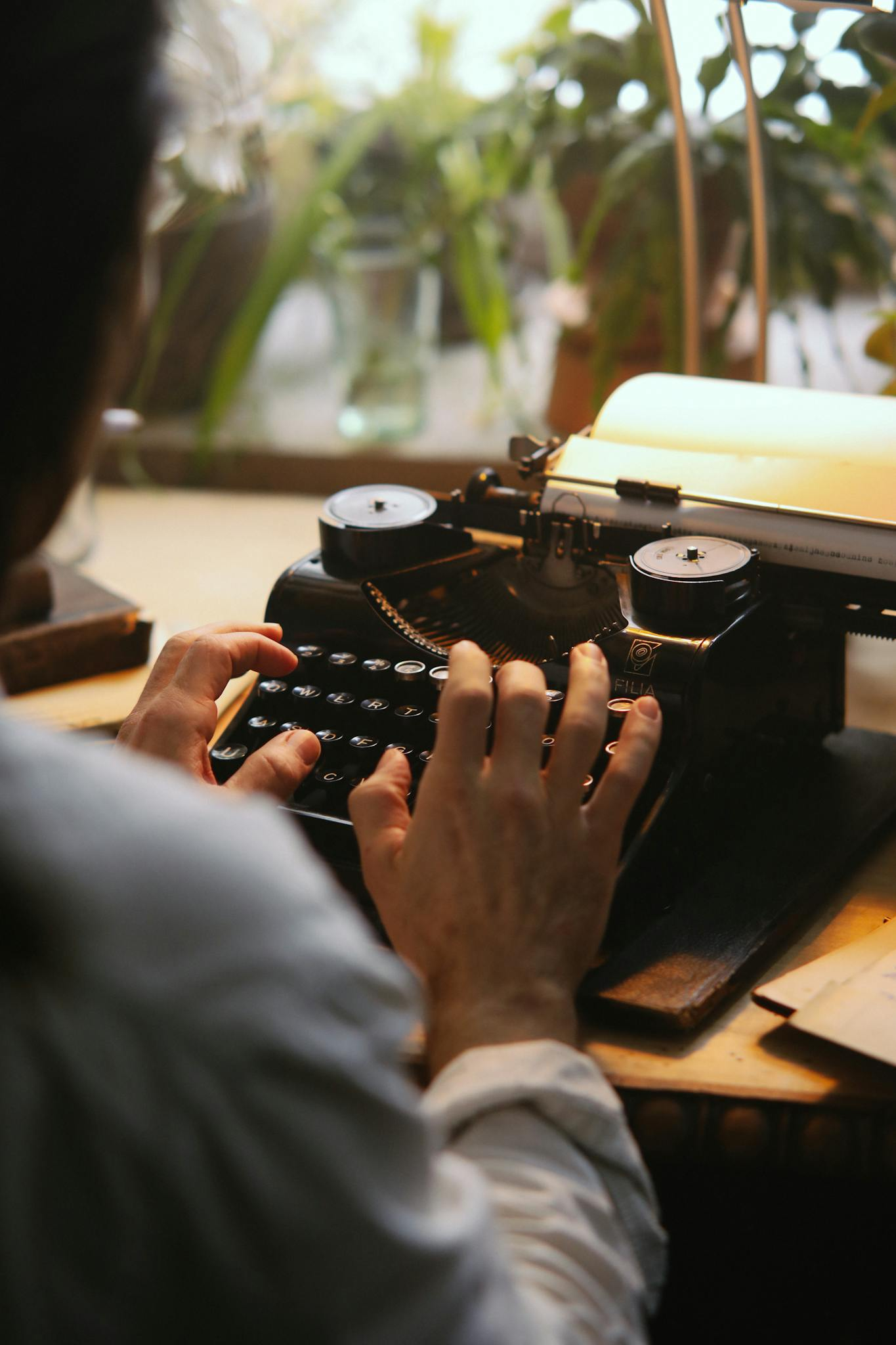 Person typing on a vintage typewriter with focus on hands. Indoor setting with natural light.